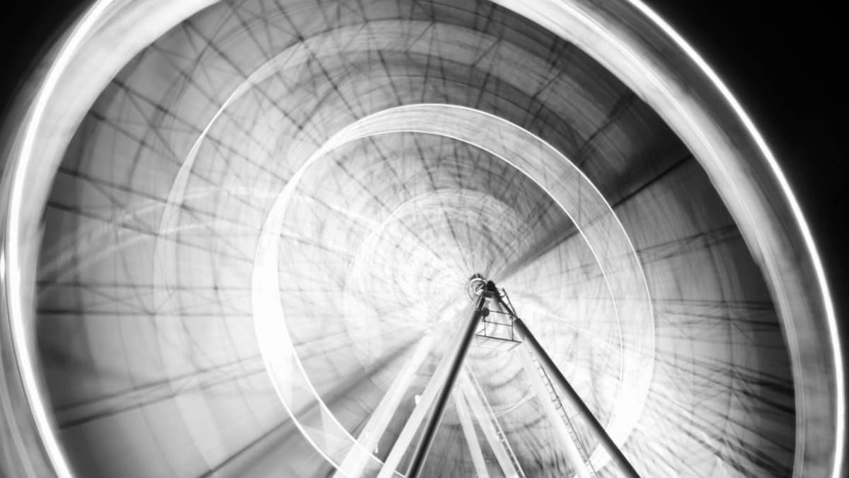 Stunning long exposure shot of a Ferris wheel in motion at night, creating a mesmerizing abstract pattern.
