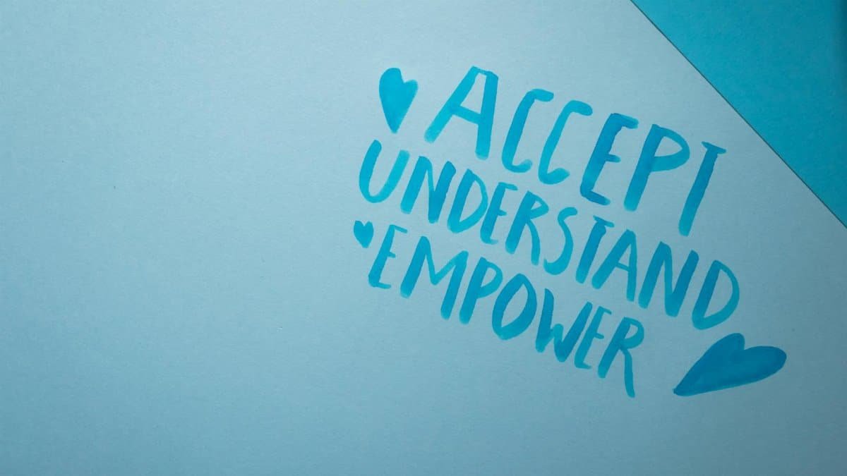 Blue background featuring handwritten words promoting acceptance, understanding, and empowerment.