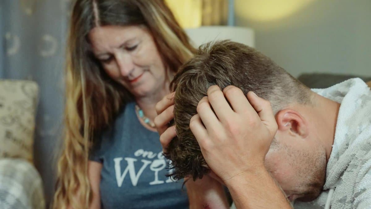 A mother provides emotional support to her stressed son indoors, conveying empathy and caring.