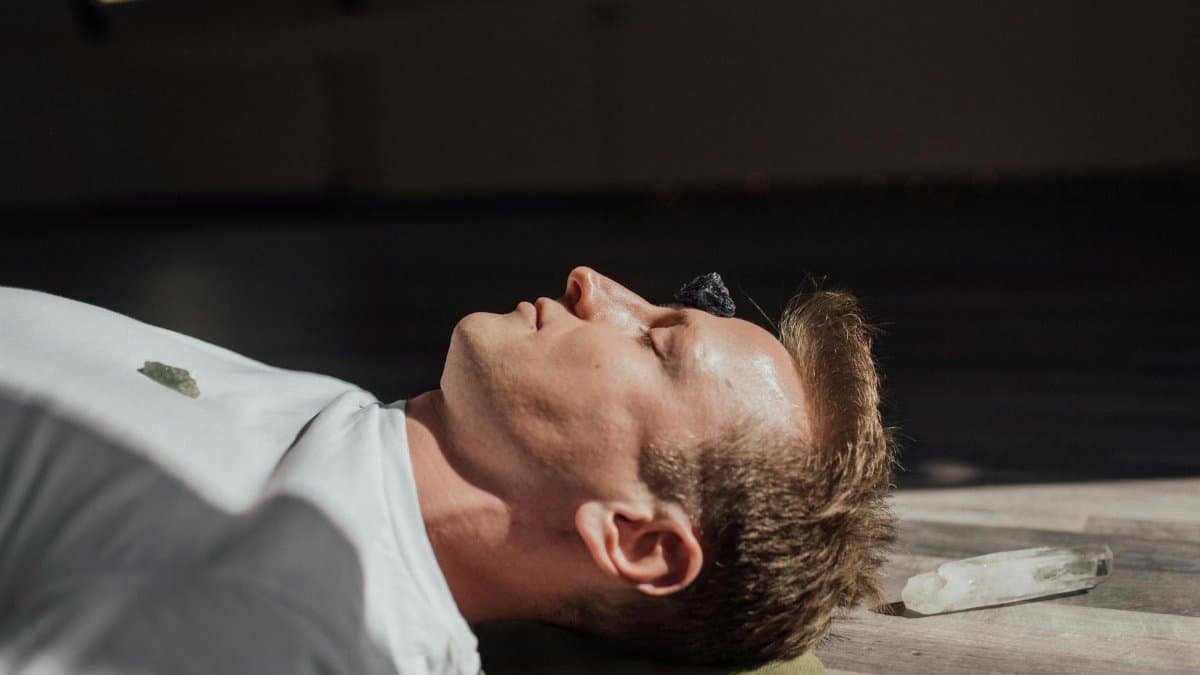 Man meditating indoors with crystals, focusing on relaxation and healing energy.