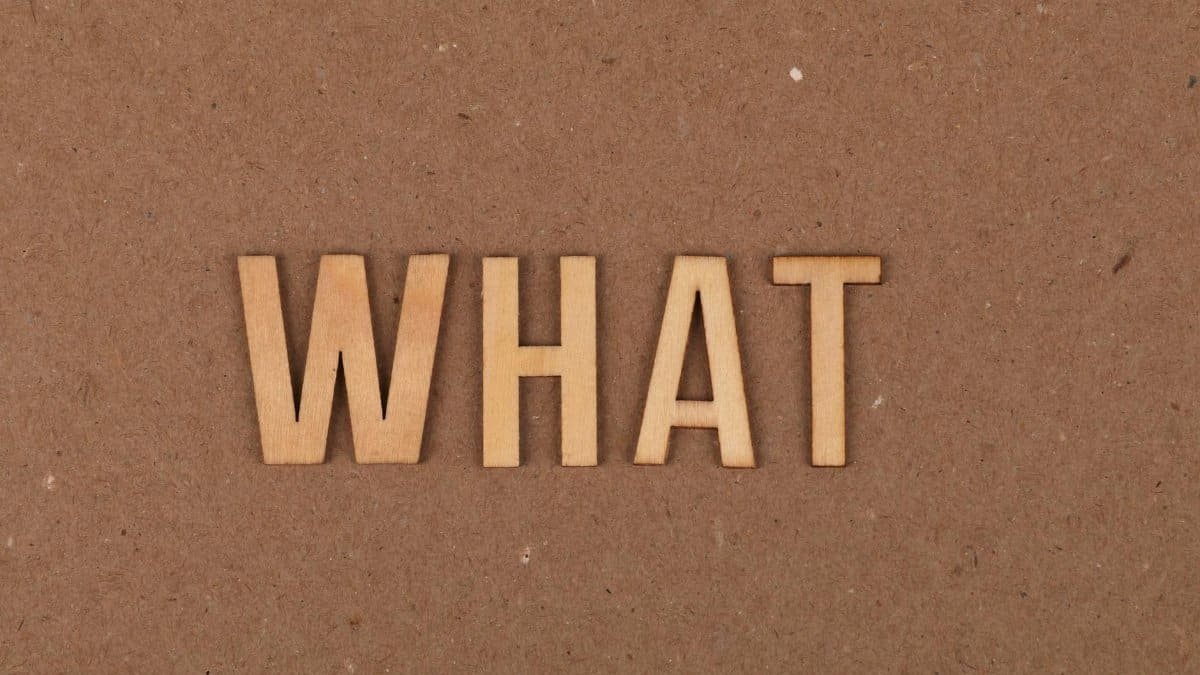 Wooden letters spelling 'What' on a brown cardboard background, close-up view.