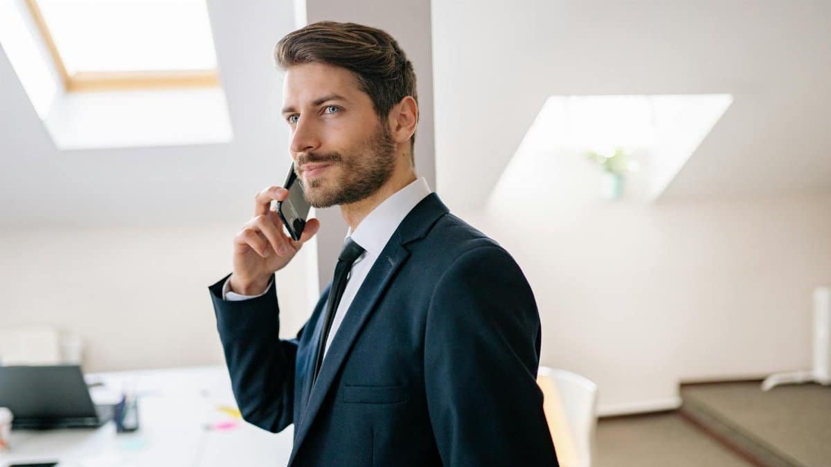 Professional businessman in a suit making a phone call in a modern office setting.