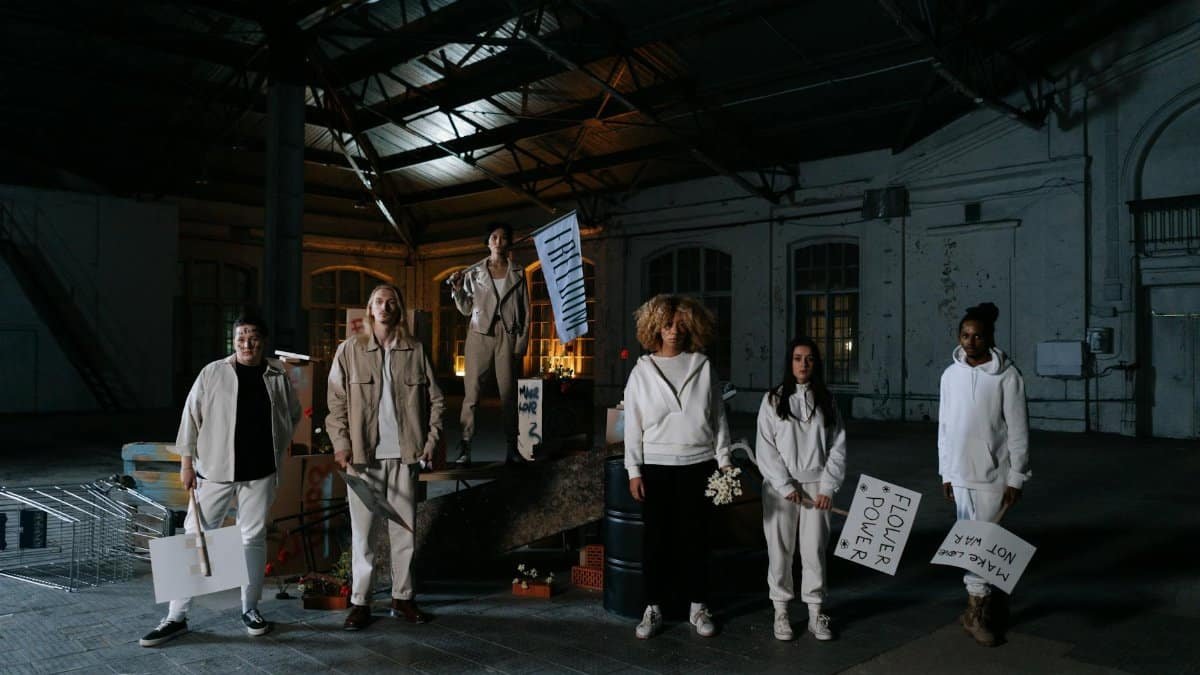 A diverse group of adults engaging in an indoor peaceful protest with signs promoting unity and freedom.