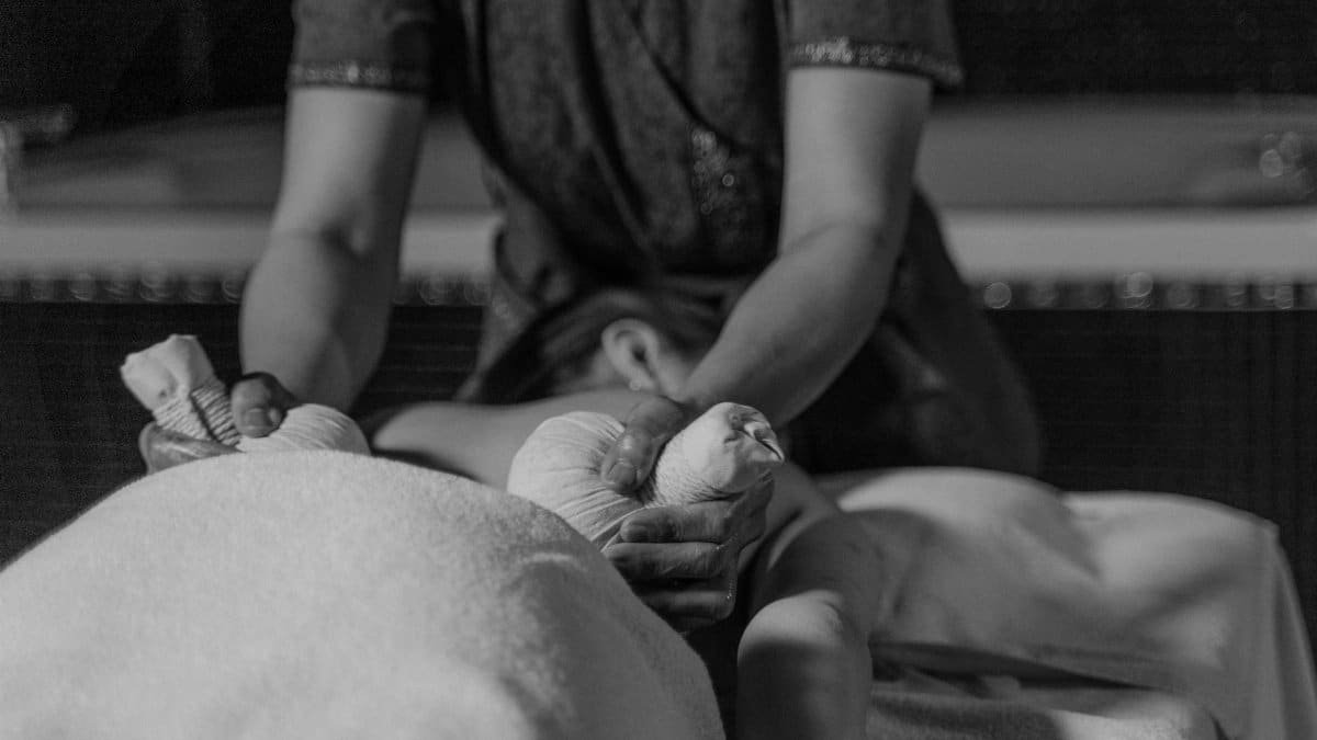Black and white photo showing a relaxing outdoor massage therapy session in progress, emphasizing tranquility.