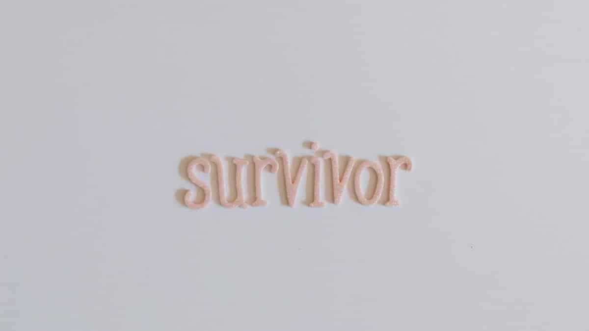 Close-up of the word 'survivor' in pink letters on a white background, symbolizing strength and resilience.