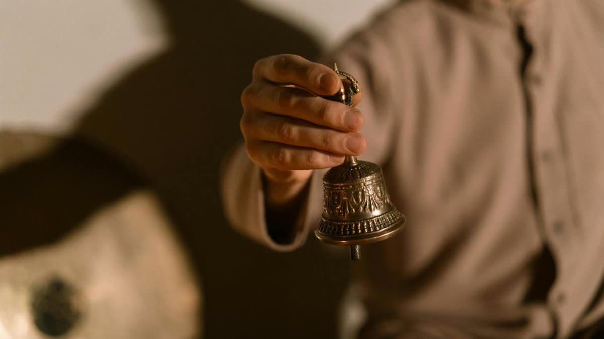 A person holding a Tibetan bell, symbolizing healing and meditation practices.