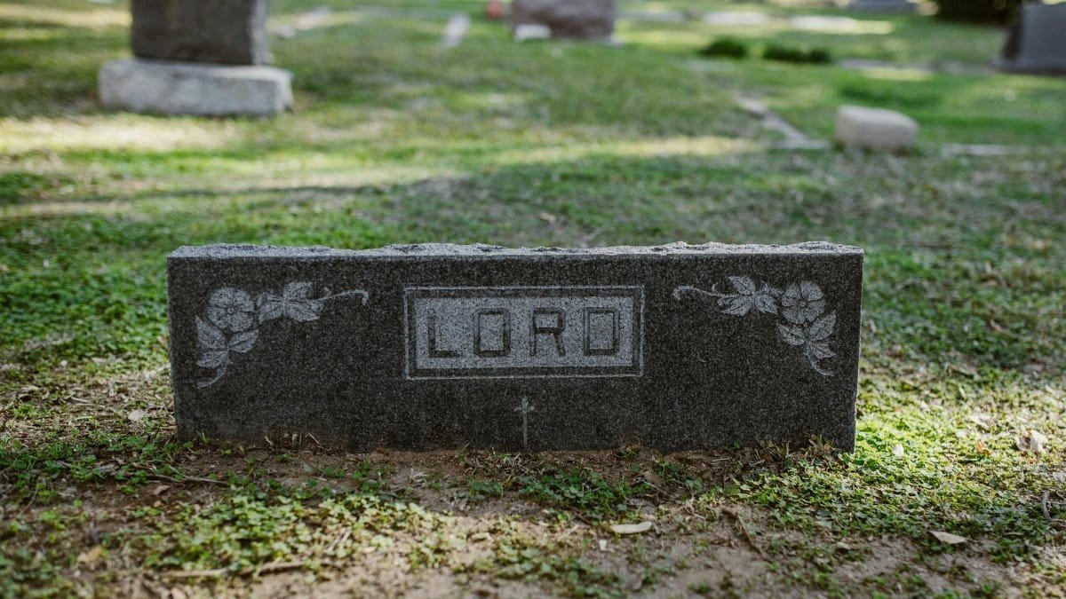 A peaceful cemetery scene featuring a gravestone marked 'Lord' surrounded by greenery.
