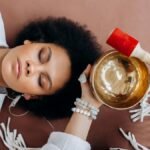 A woman experiencing sound healing therapy with a Tibetan singing bowl indoors