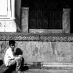 A young boy sitting on historic steps in Delhi, conveying solitude and contemplation.
