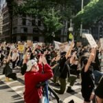 A group of protesters kneeling on a city street holding signs for Black Lives Matter, advocating justice and equality.