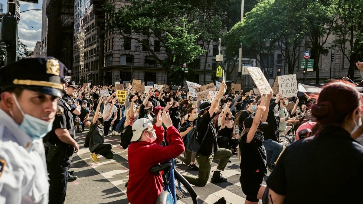 A group of protesters kneeling on a city street holding signs for Black Lives Matter, advocating justice and equality.