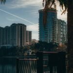 View of Orlando's modern skyline reflecting on a tranquil lake, surrounded by trees.