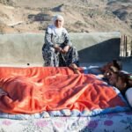 Family on a rooftop in a scenic mountainside location with colorful blankets.