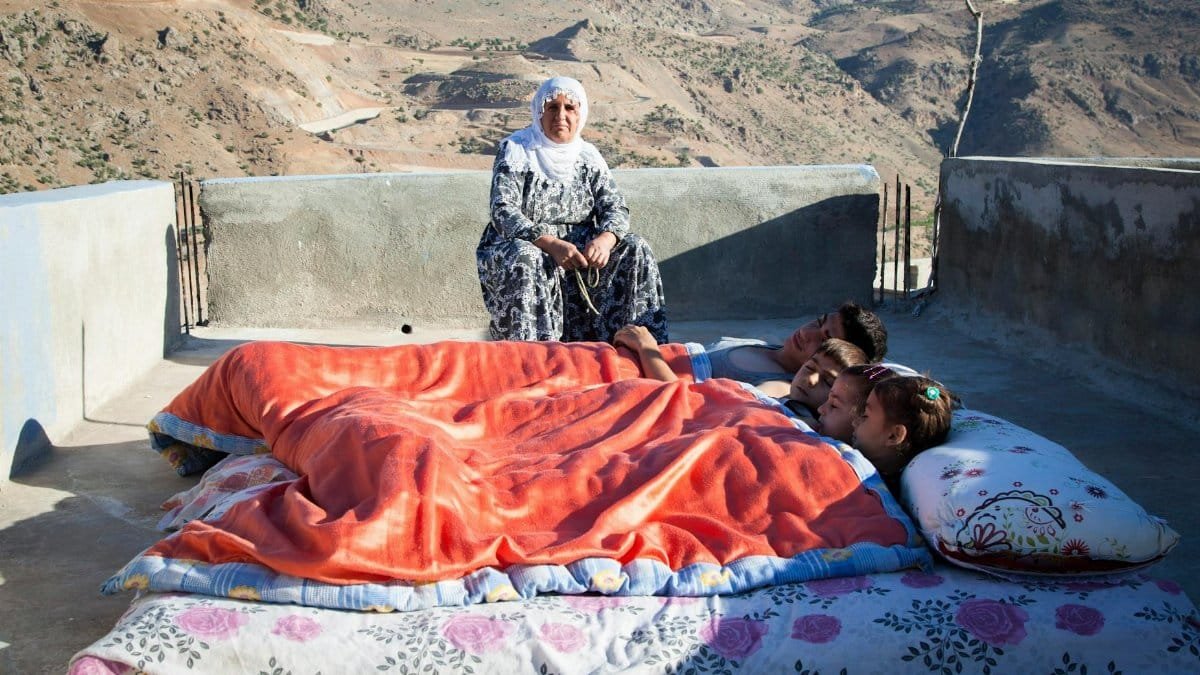 Family on a rooftop in a scenic mountainside location with colorful blankets.