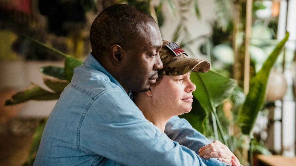 A soldier and partner share a loving embrace indoors, symbolizing reunion and love.
