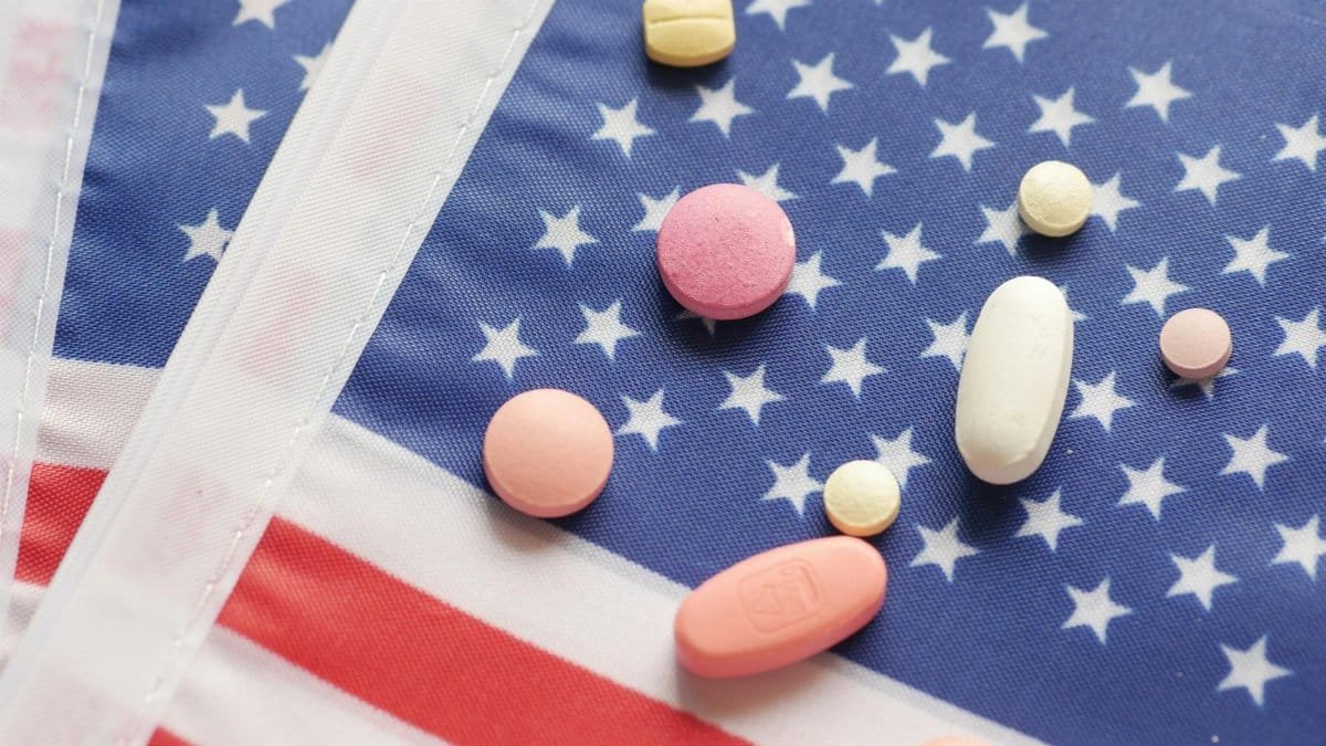 Various pills scattered over a printed American flag symbolizing healthcare.