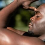 Close-up of an African American man practicing mindful meditation outdoors in sunlight.