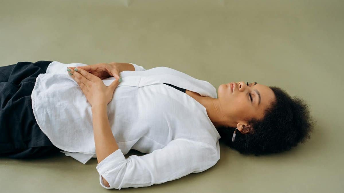 African American woman lying down with eyes closed, embodying relaxation and wellness. Perfect for wellness and mindfulness themes.