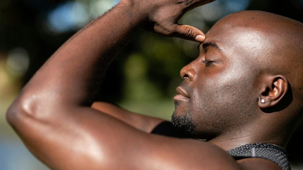 Close-up of an African American man practicing mindful meditation outdoors in sunlight.