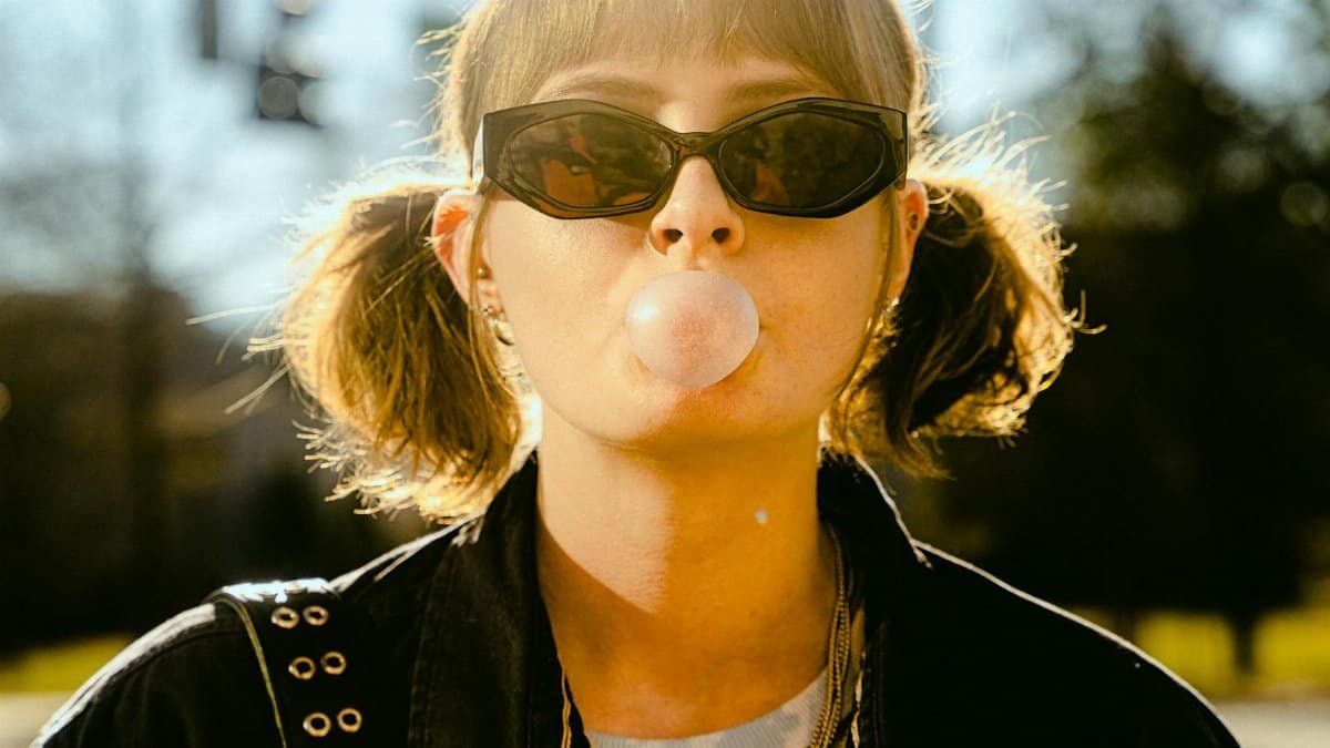 Stylish young woman with sunglasses blowing bubble gum outdoors in Atlanta, GA.