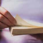 Hand turning a book page, capturing an intimate moment of reading.