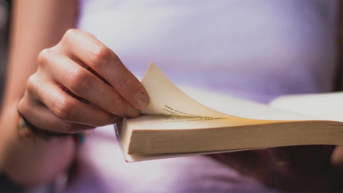 Hand turning a book page, capturing an intimate moment of reading.