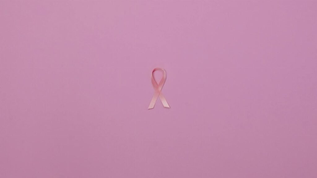 Pink ribbon on pastel background symbolizing breast cancer awareness.