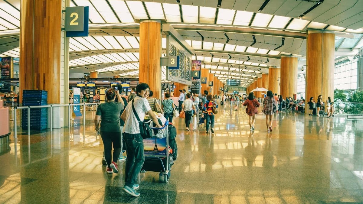 Travelers bustling through Singapore Changi Airport terminal, highlighting the dynamic and vibrant atmosphere of international travel.