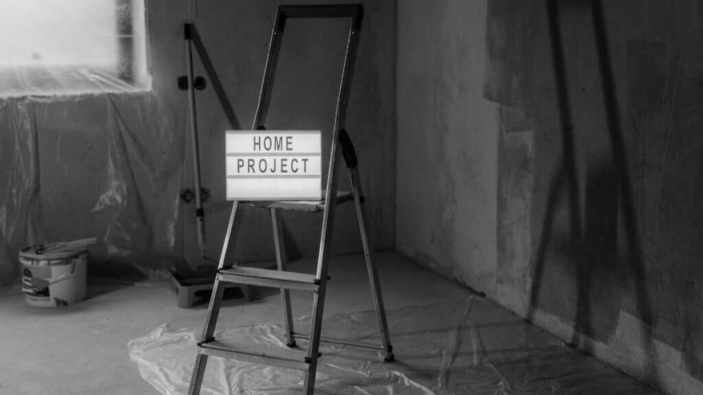 Black and white image of a step ladder with a 'home project' sign in a renovation setting.