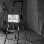 Black and white image of a step ladder with a 'home project' sign in a renovation setting.