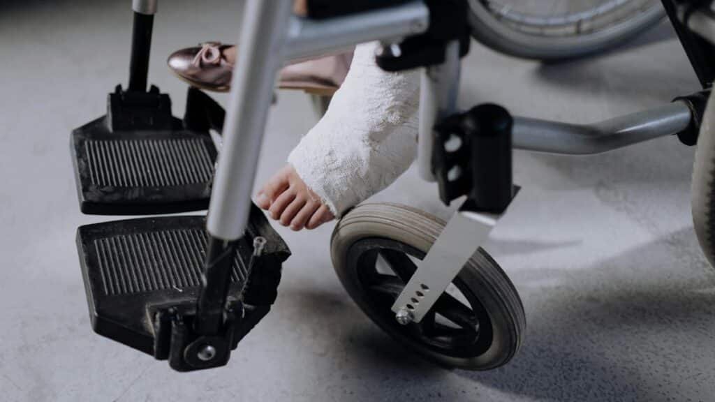 Close-up of an injured foot in a cast resting on a wheelchair, indoors.