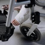 Close-up of an injured foot in a cast resting on a wheelchair, indoors.