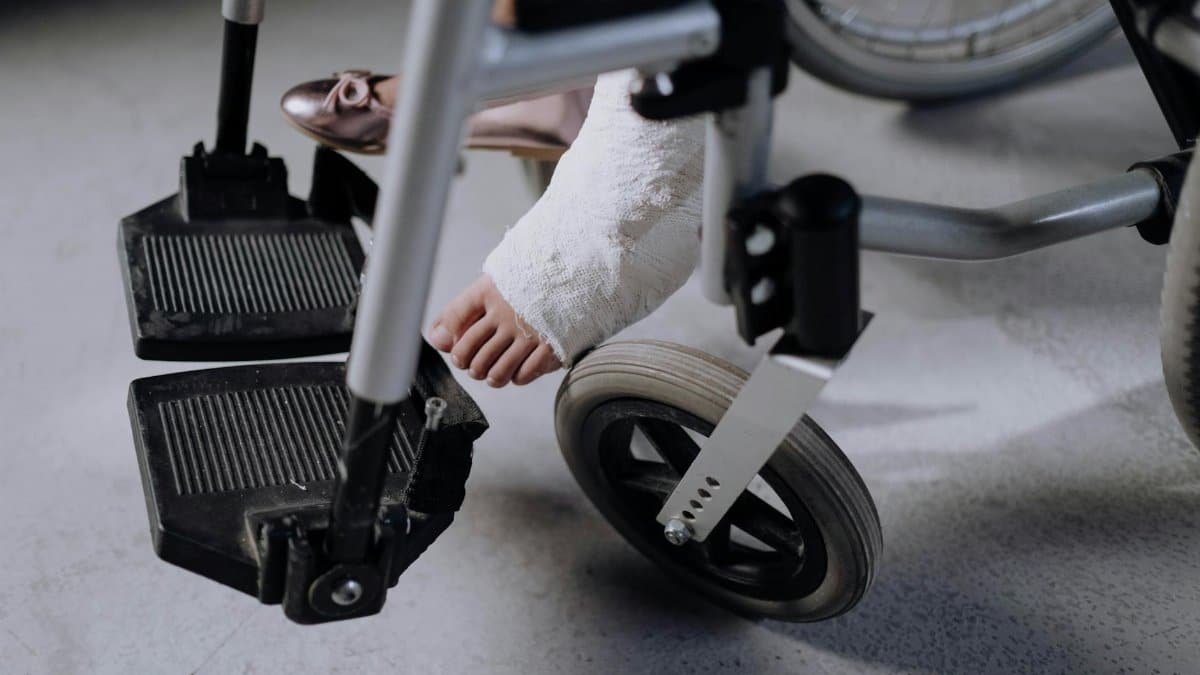 Close-up of an injured foot in a cast resting on a wheelchair, indoors.