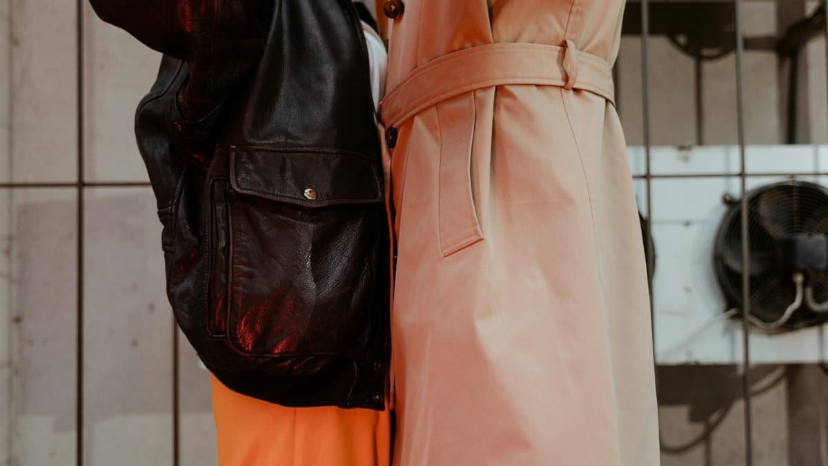 Close-up of a fashionable couple wearing leather jacket and trench coat embracing indoors.