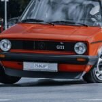 Vintage red GTI sports car in action on a city street track, showcasing its speed and design.