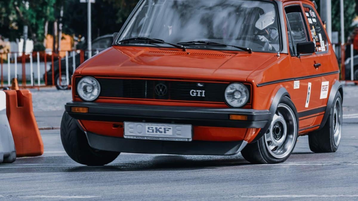 Vintage red GTI sports car in action on a city street track, showcasing its speed and design.
