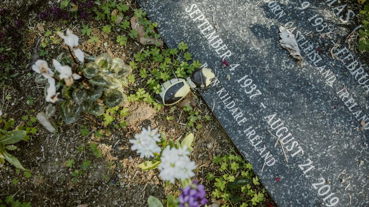 A gravestone adorned with flowers in a tranquil cemetery, symbolizing remembrance and peace.
