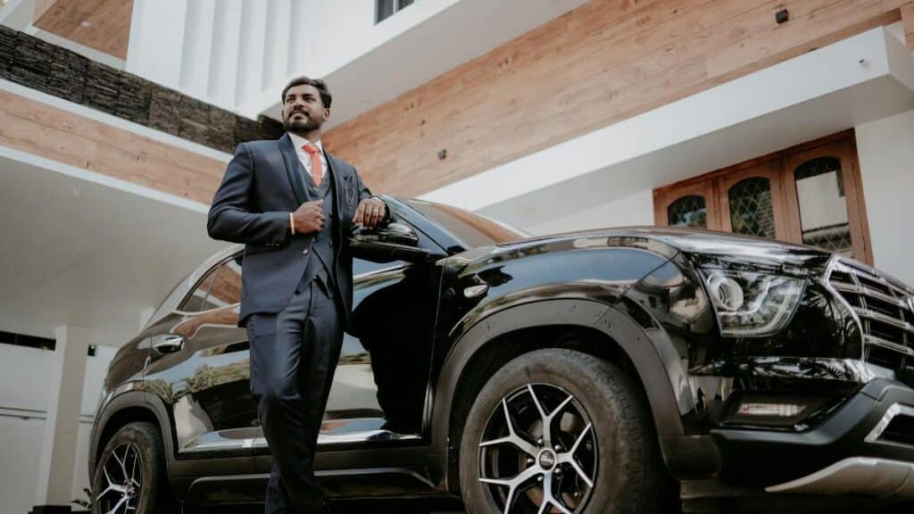 An Indian groom poses elegantly in front of a modern residence, exuding confidence.