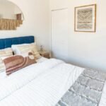 Contemporary bedroom with plush pillows, art, and neon sign in Philadelphia.