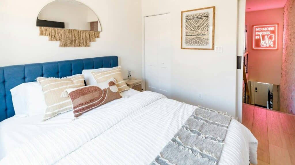 Contemporary bedroom with plush pillows, art, and neon sign in Philadelphia.