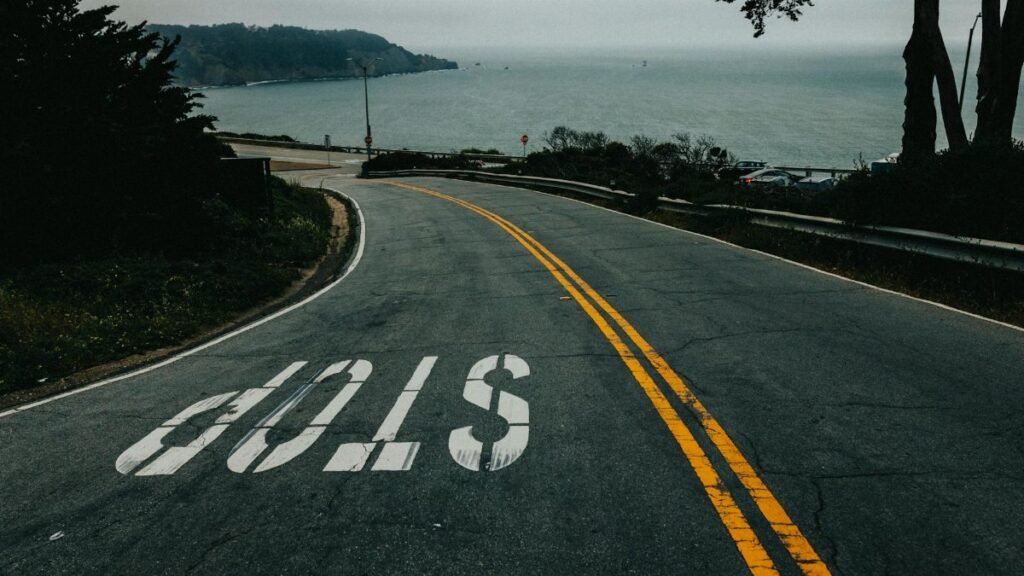 Curved road in San Francisco leading to the ocean with a clear stop sign.
