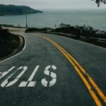 Curved road in San Francisco leading to the ocean with a clear stop sign.