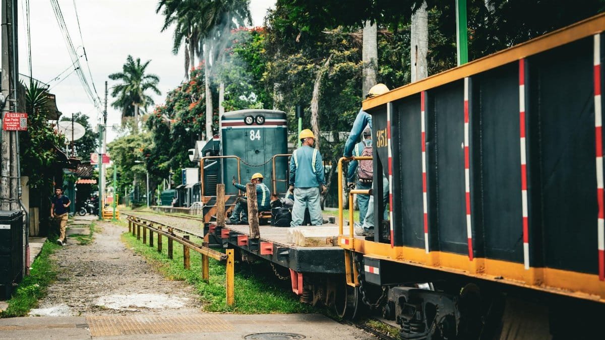 Workers on train tracks surrounded by lush greenery in San José, Costa Rica.