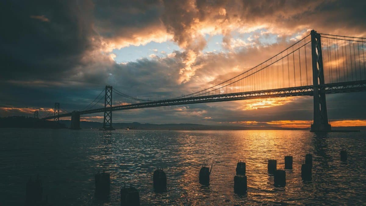 Stunning sunset view of the Bay Bridge in San Francisco reflecting on water.