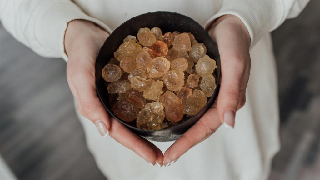 A close-up view of hands holding a bowl of natural healing crystals.