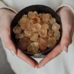 A close-up view of hands holding a bowl of natural healing crystals.