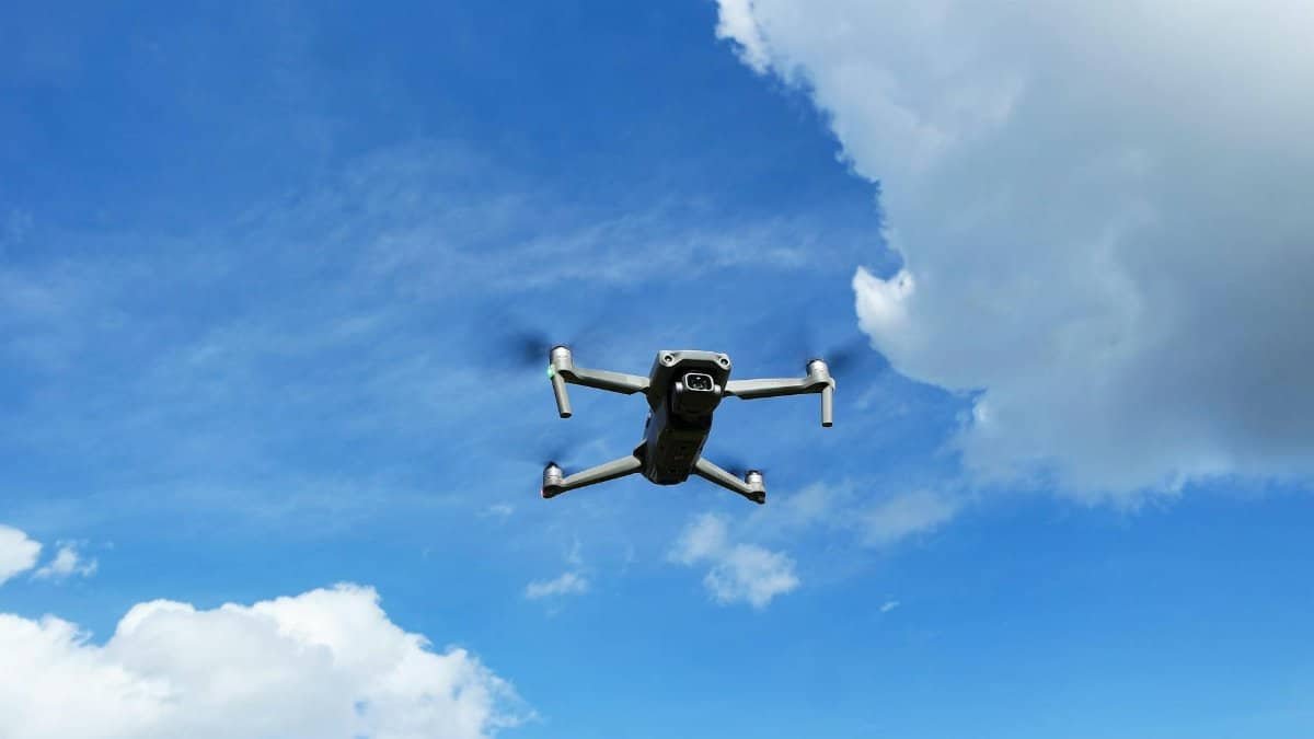 Captivating aerial shot of a drone soaring high in the blue sky with fluffy white clouds.