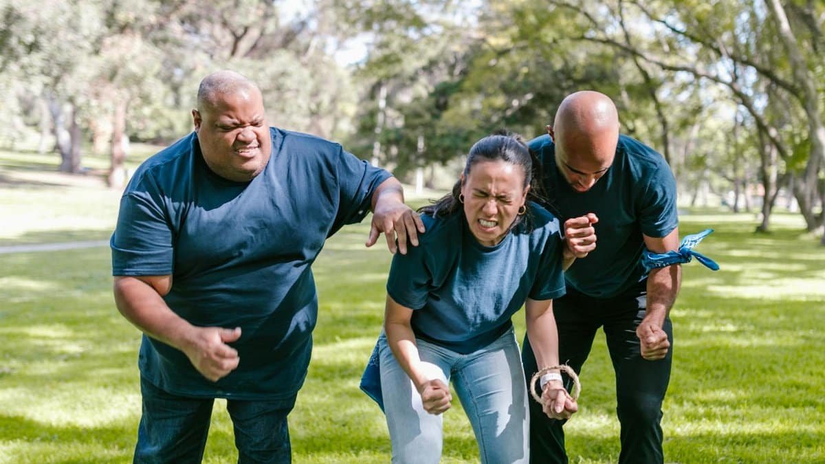 A group of diverse adults engaging in a fun team-building activity outdoors.