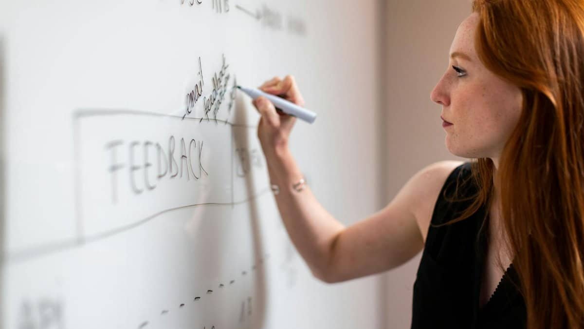 Focused woman writing on a whiteboard during a business planning session.