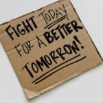 Cardboard sign with 'Fight today for a better tomorrow!' message on a white background.